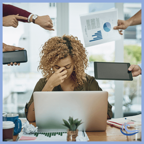 Woman with head in hand in front of a laptop and many requests all around her.